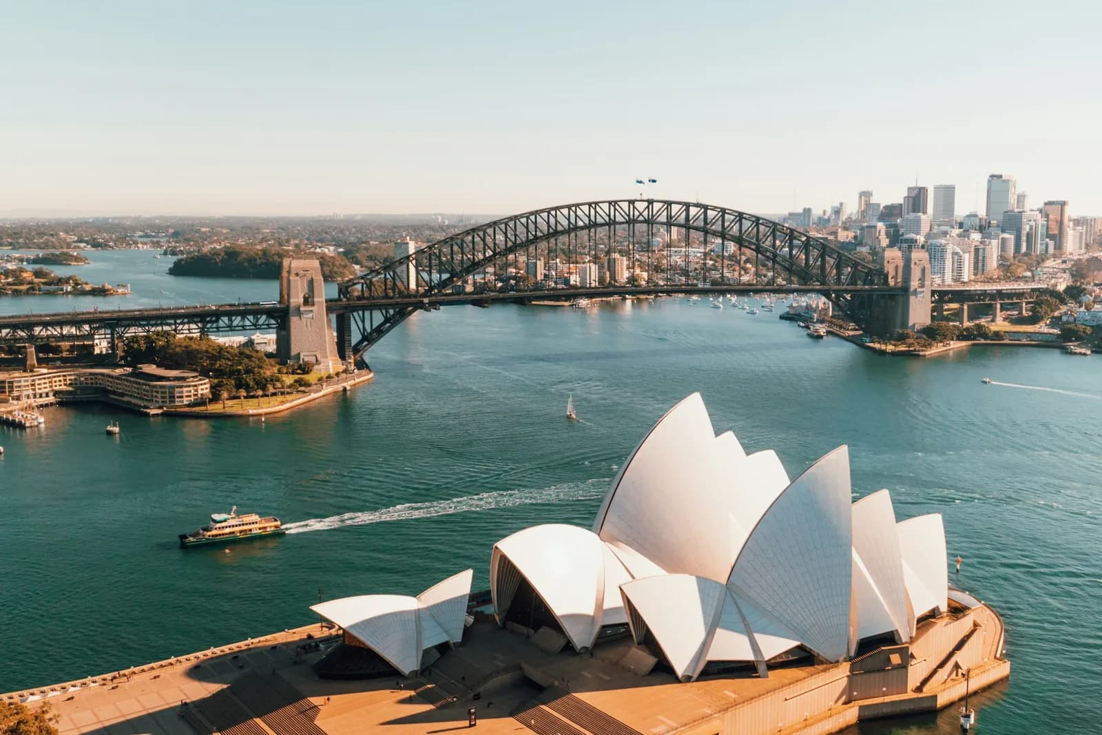 Nhà hát Opera Sydney và cầu Sydney Harbour nhìn từ trên cao, một chiếc phà rẽ nước trên vịnh