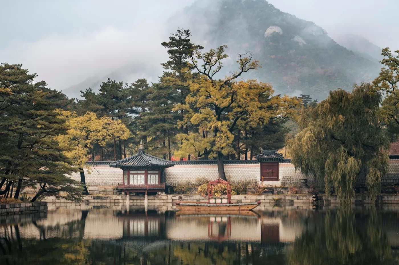 Đình cổ kiểu Hàn Quốc bên mặt hồ phẳng lặng, hàng cây thu và ngọn núi phủ sương ở Seoul